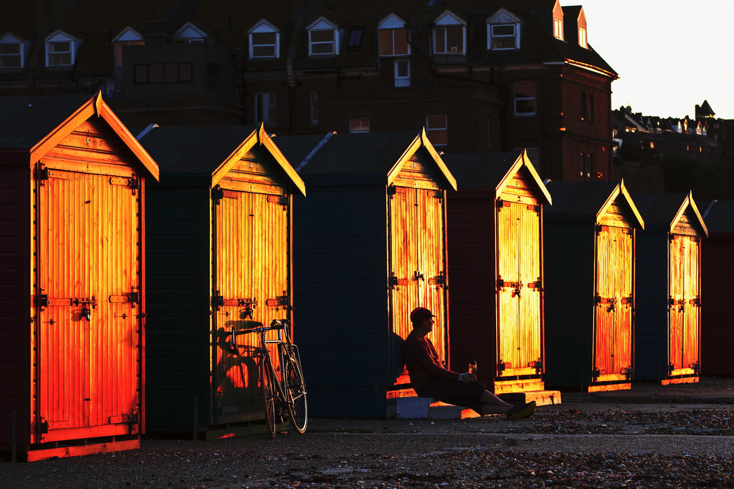 Cycling in Sussex - a cyclist pedals up Cambridge Road in Hastings in twilight past a row of coloured houses