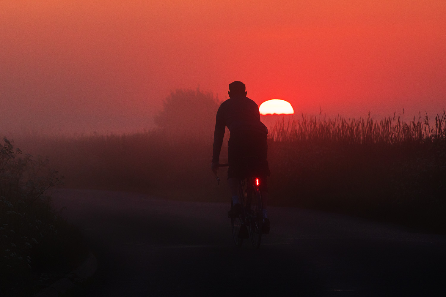 Red Sun in Morning - cyclist looking at glowing red sun rise