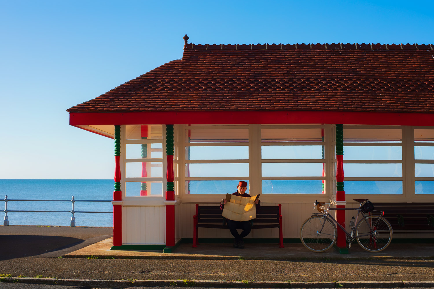 Man with bicycle looking at map on a bench by the seaside